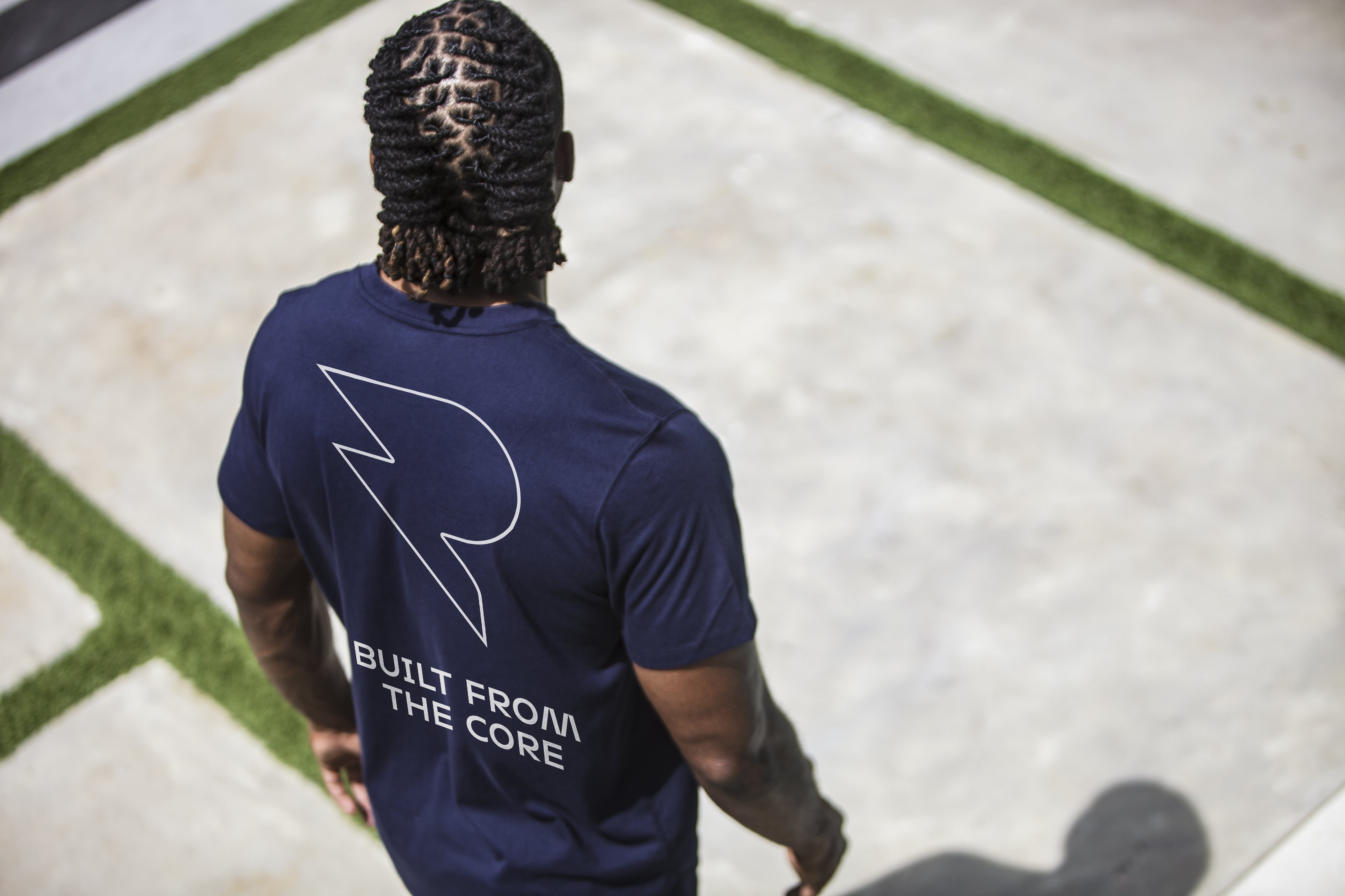 Person with braided hair wearing a navy shirt with text 'Built From The Core.'