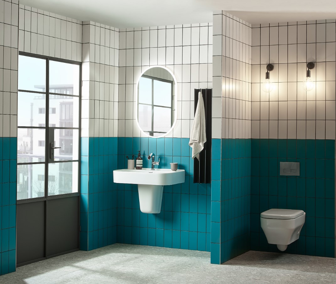 Modern bathroom with blue and white tiles, sink, mirror, and wall-mounted toilet.