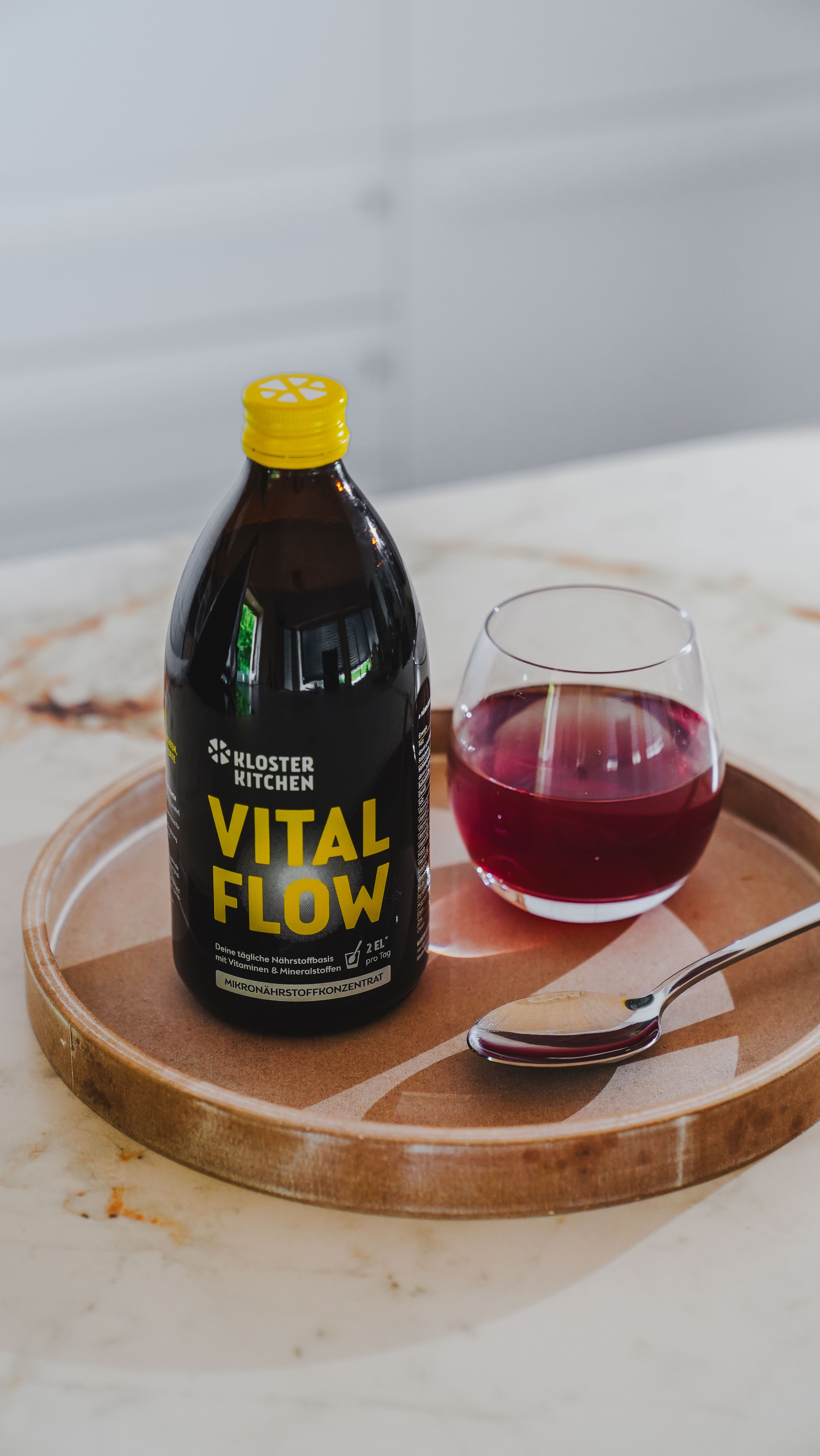 Botella de Vital Flow y un vaso de líquido rojo en una bandeja.