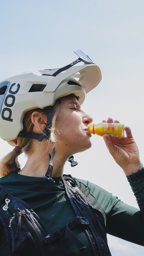 Person wearing a helmet and gear drinking from a small bottle.