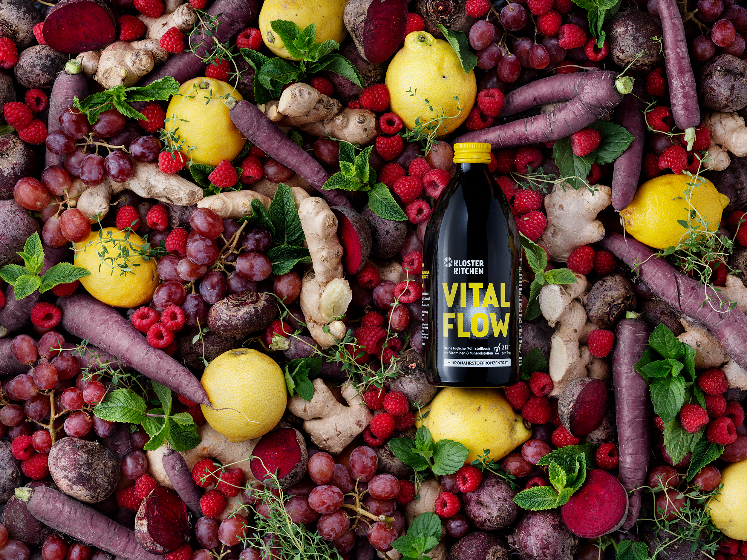 Assorted fruits and vegetables surrounding a bottle labeled 'Vital Flow.