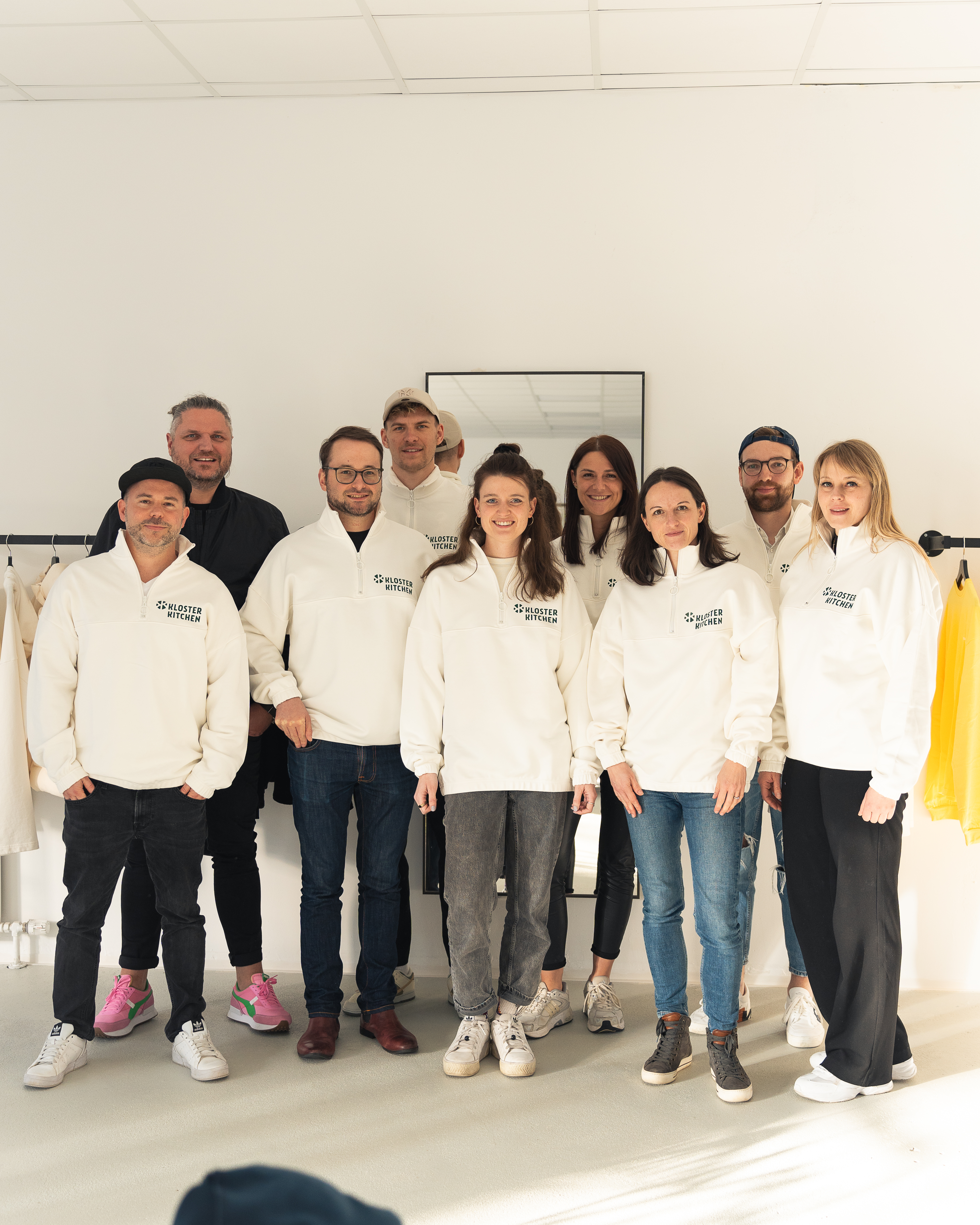A group of people wearing matching white sweatshirts posing indoors.