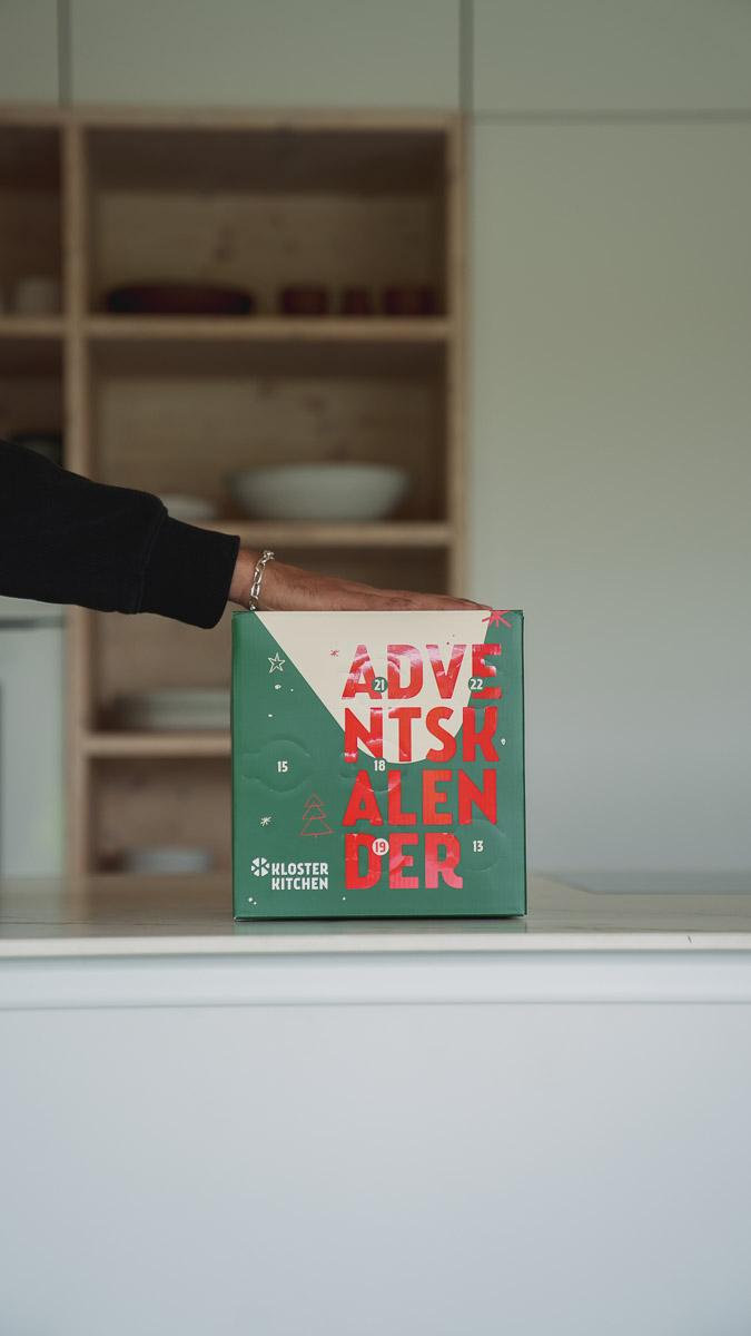 Person holding a green advent calendar box in a kitchen.