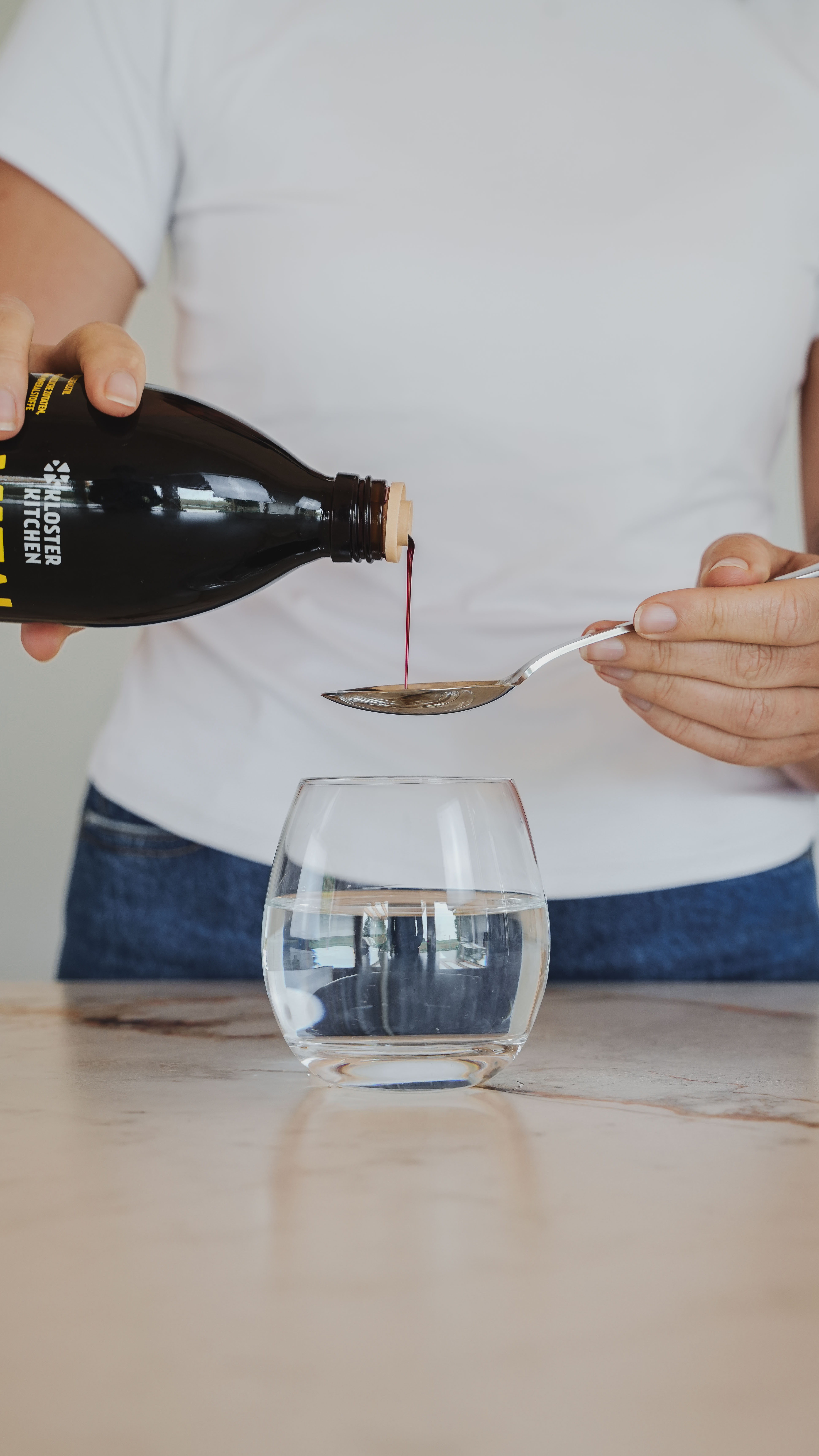 Persona que vierte el líquido de la botella en una cuchara sobre el vaso.