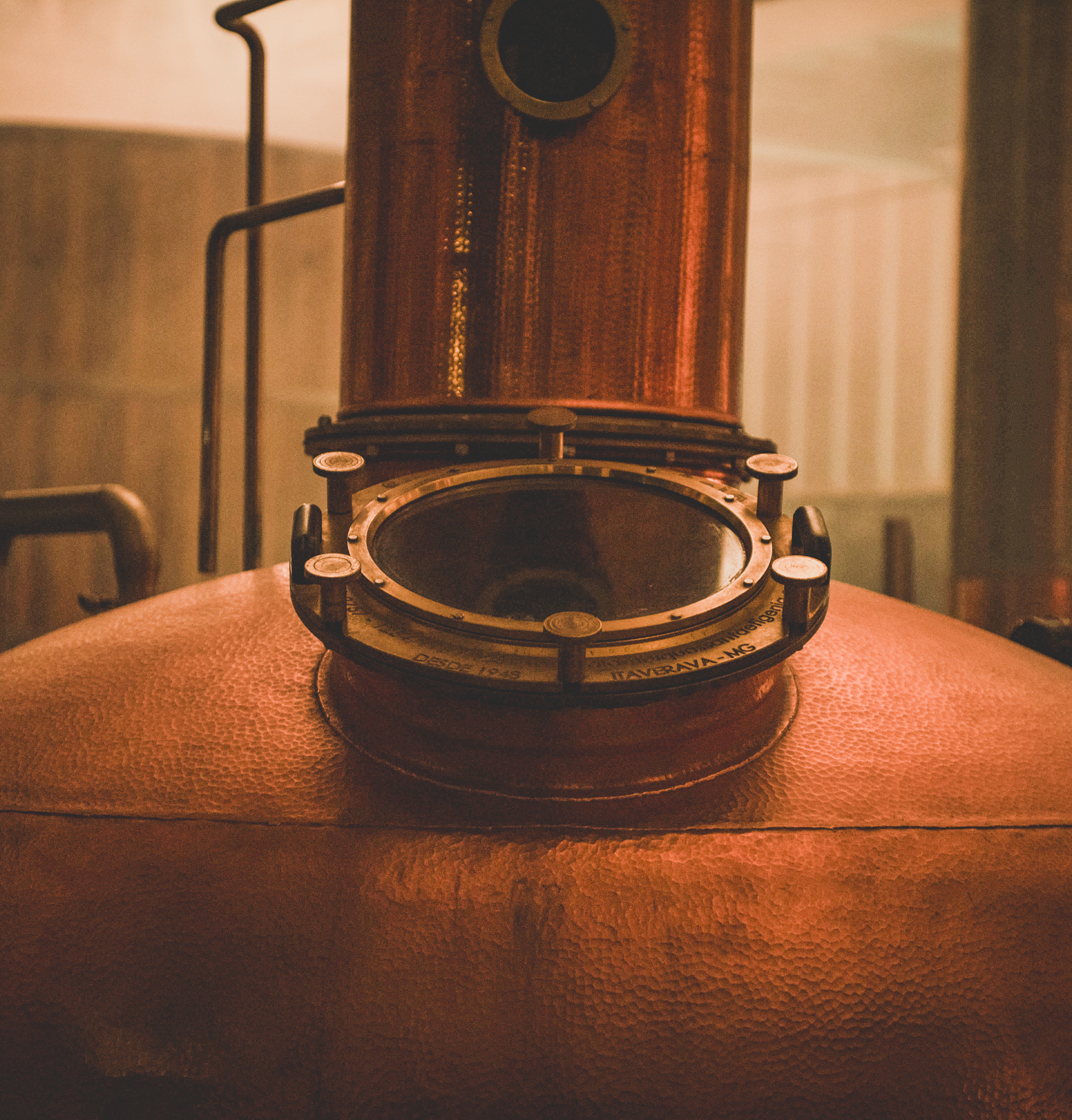 Copper distillation apparatus with circular glass window and pipes.