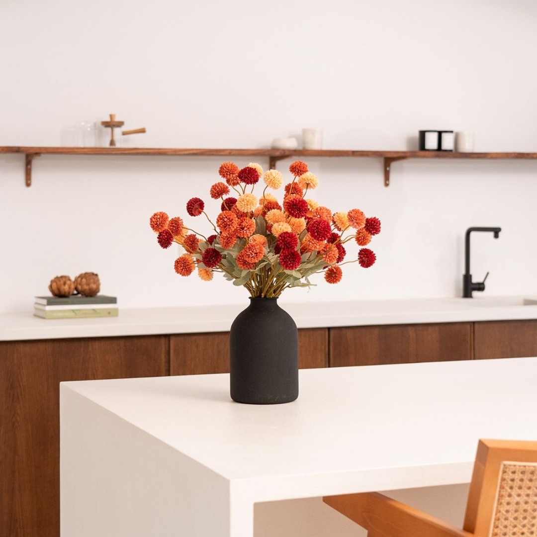 Vase with red and orange flowers on a white kitchen counter.