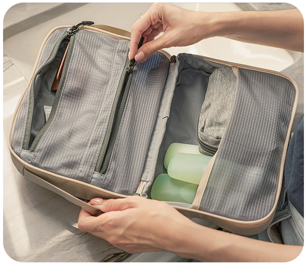 Person organizing travel bag with toiletries and zippered compartments.