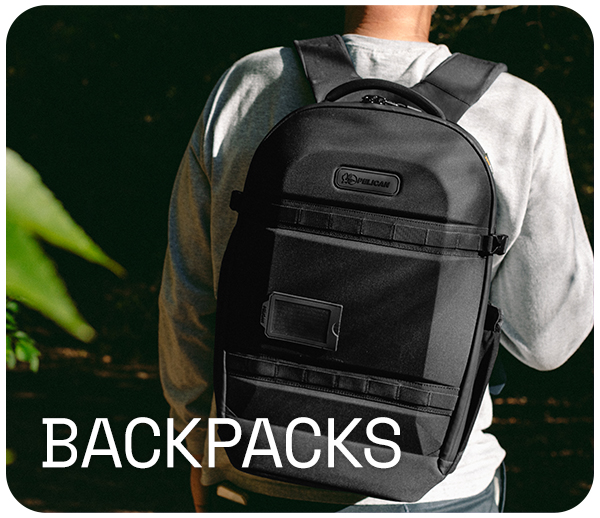 Person wearing a black backpack outdoors with text 'BACKPACKS'.