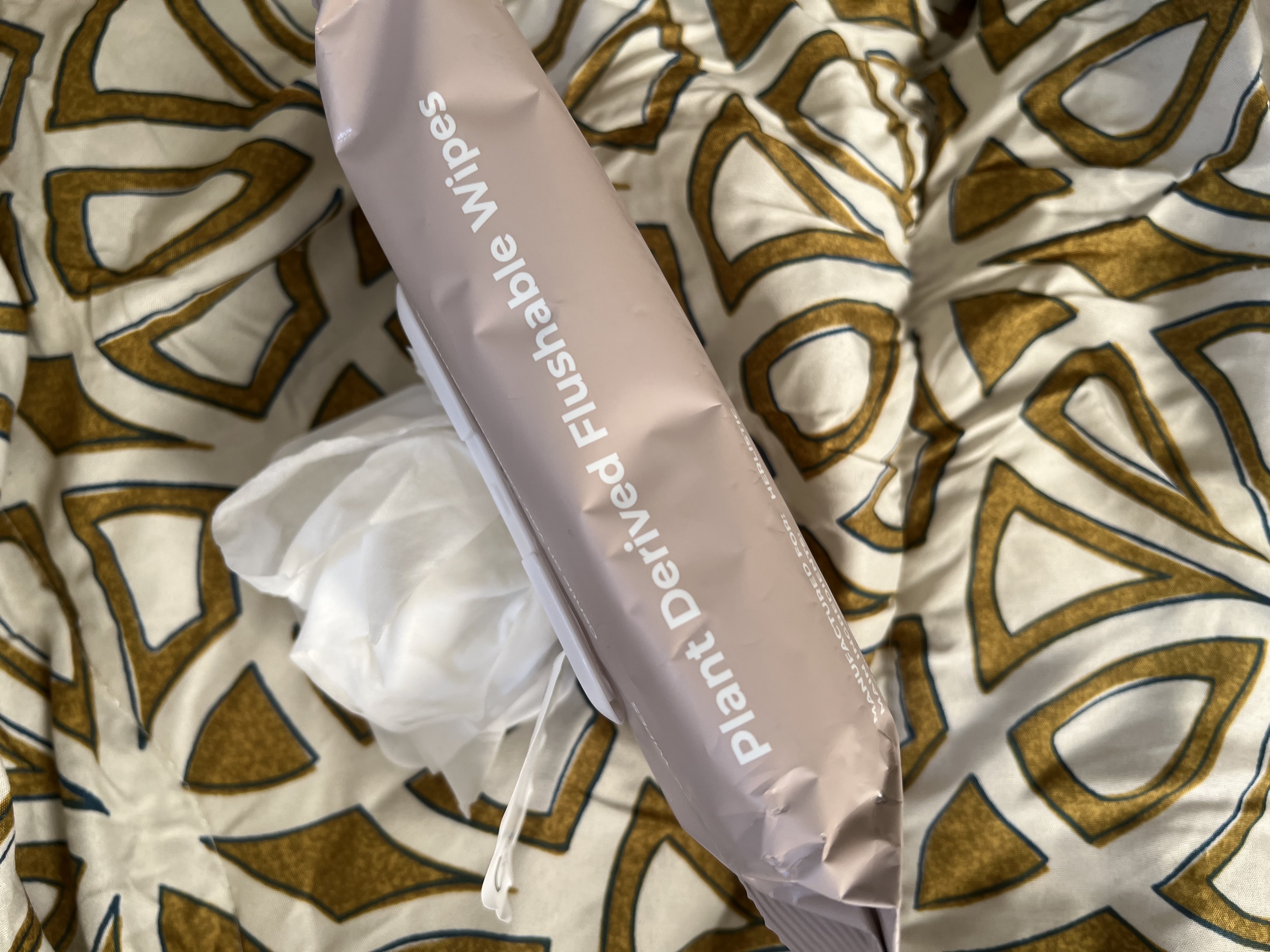 Package of plant-derived flushable wipes on patterned fabric.