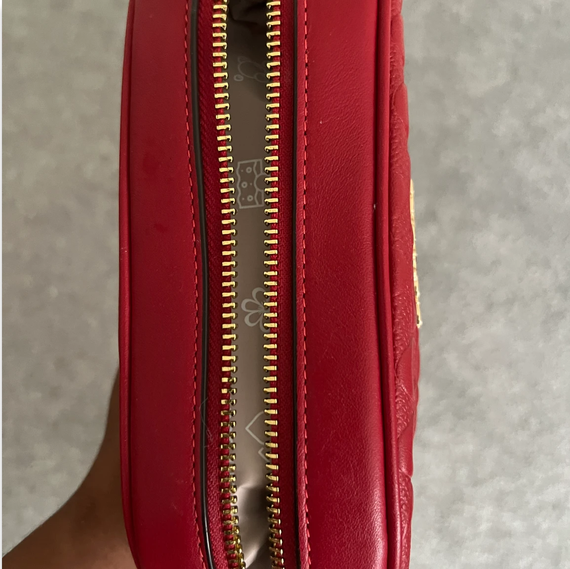 Close-up of a red leather bag with a gold zipper.