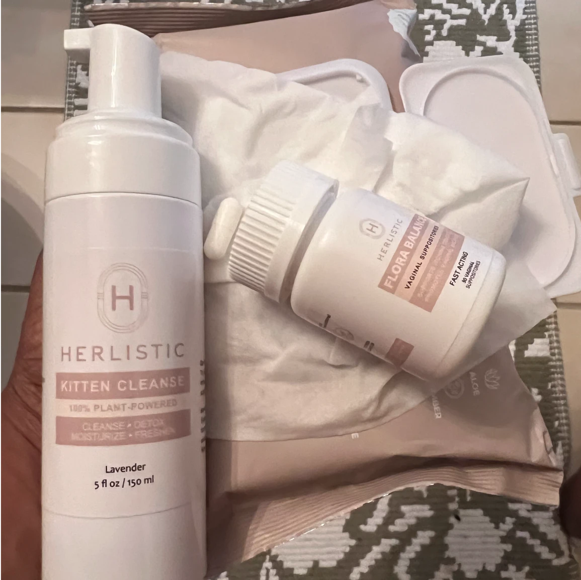 Two Herlistic products on a patterned surface: Kitten Cleanse and Flora Balance.