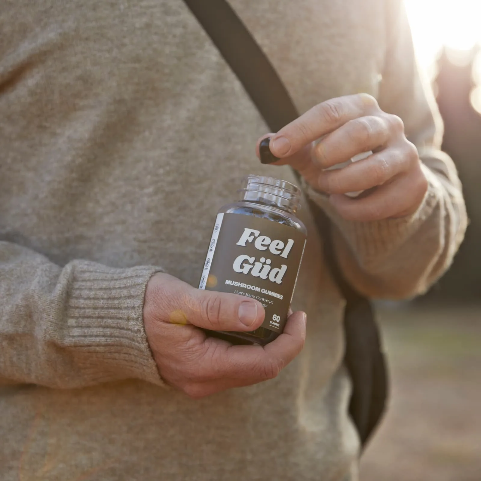 Person holding a jar of mushroom gummies outdoors.