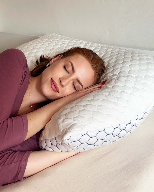 Person sleeping on a textured pillow, wearing a maroon top.