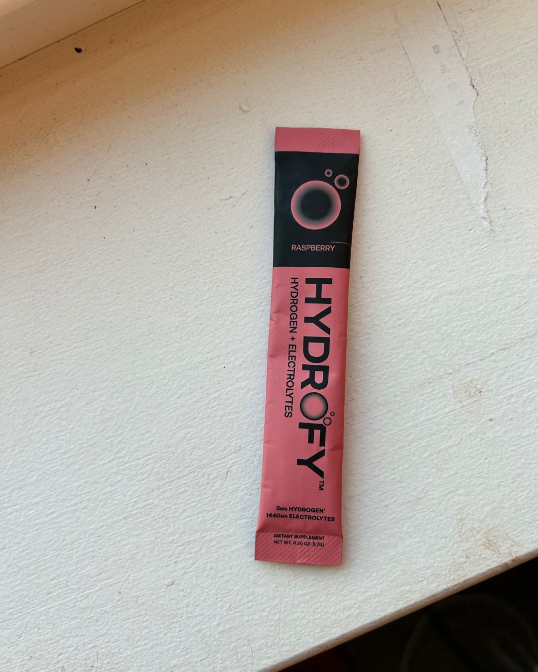 Pink raspberry-flavored electrolyte supplement packet on a light surface.