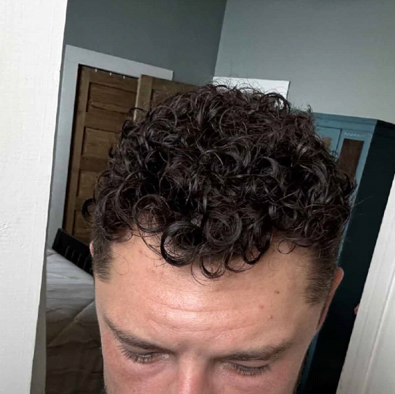 Person with short, curly brown hair is looking down.