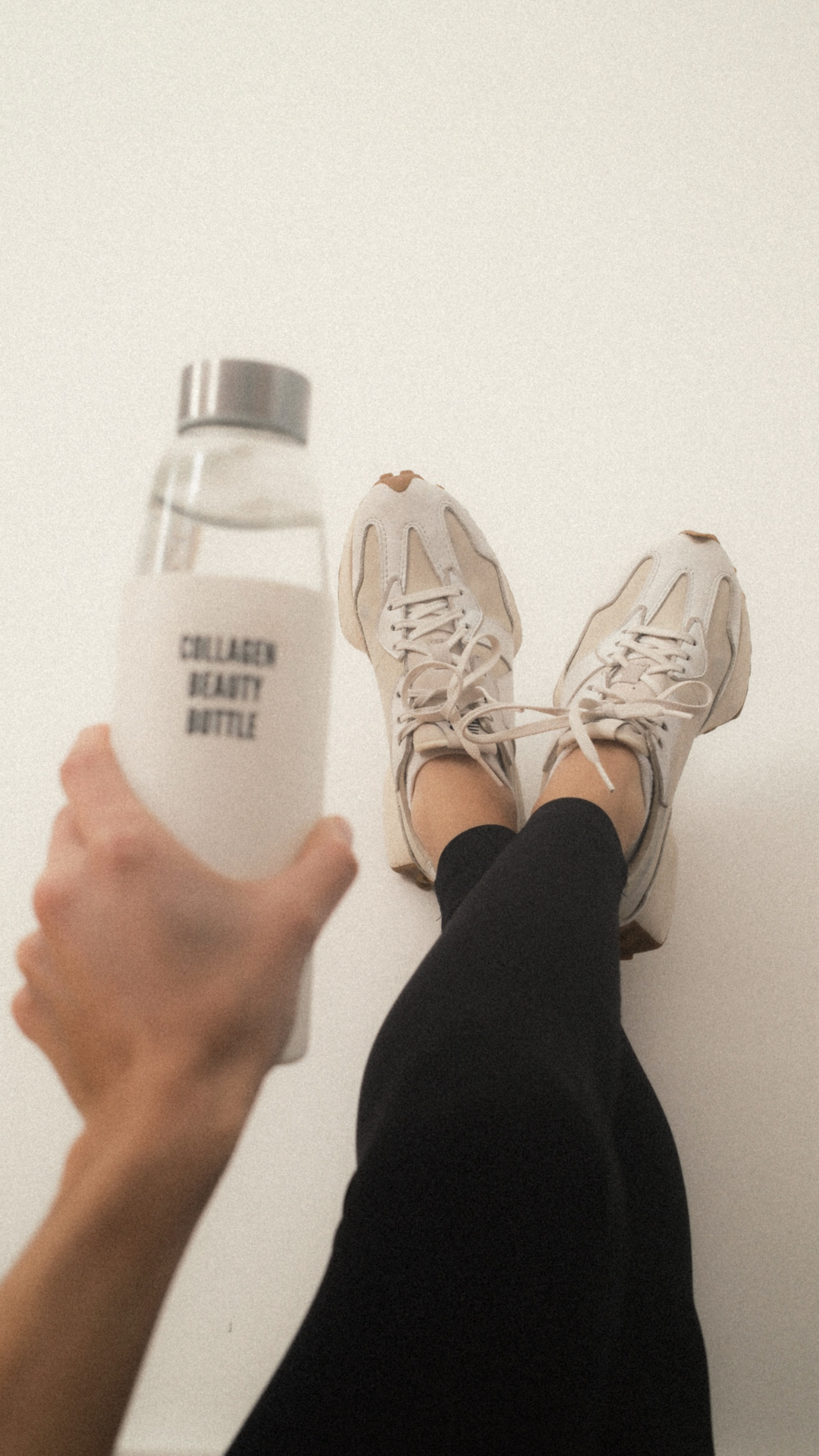 Person holding a bottle labeled 'Collagen Beauty Bottle' with feet in sneakers visible.