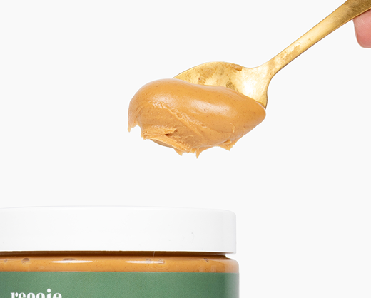 Spoonful of peanut butter above a jar with a white lid.