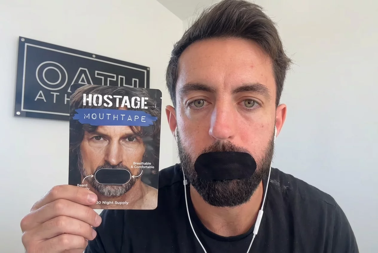 Person with mouth taped, holding 'Hostage Mouth Tape' packaging.