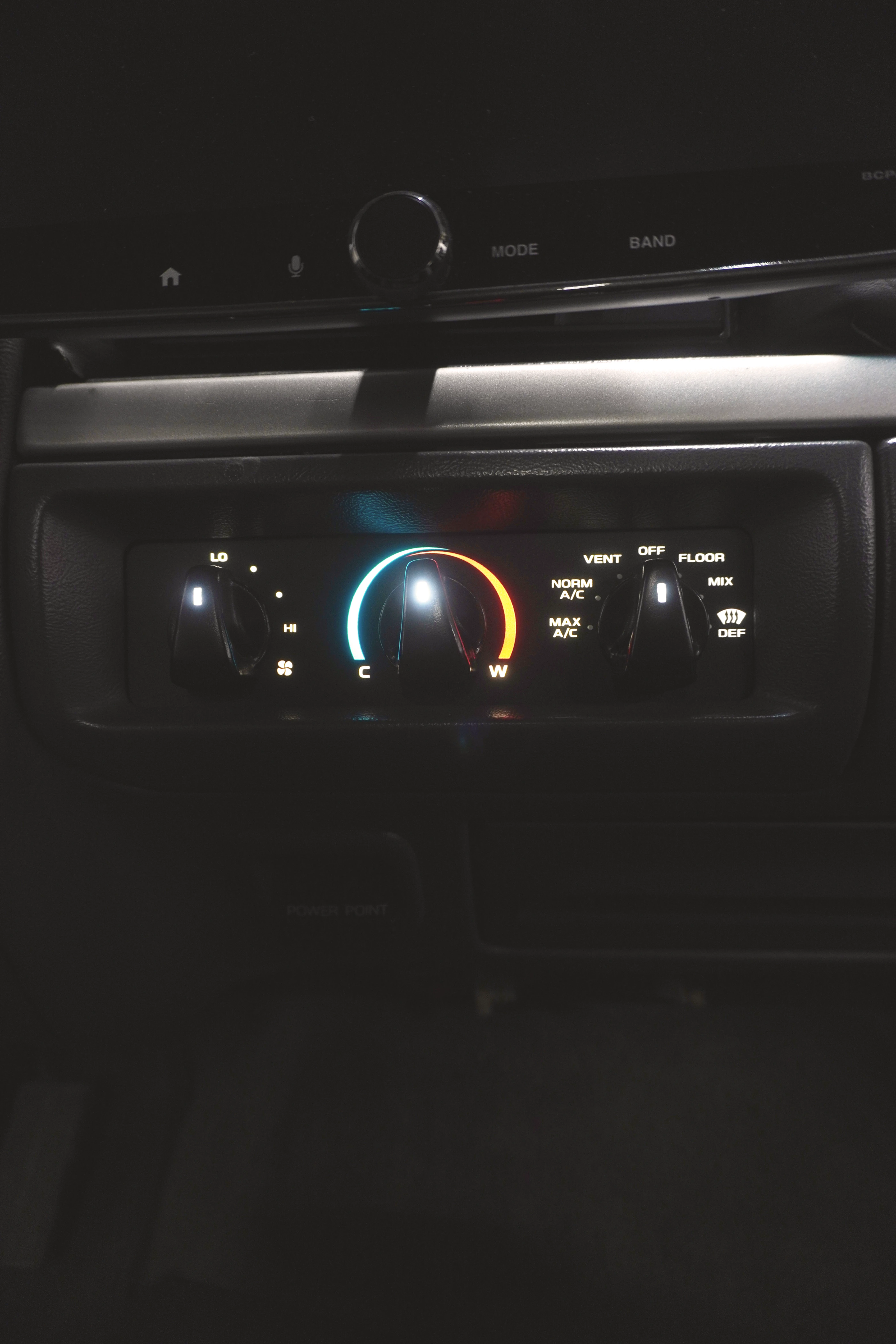 Car climate control panel with temperature and fan speed dials.