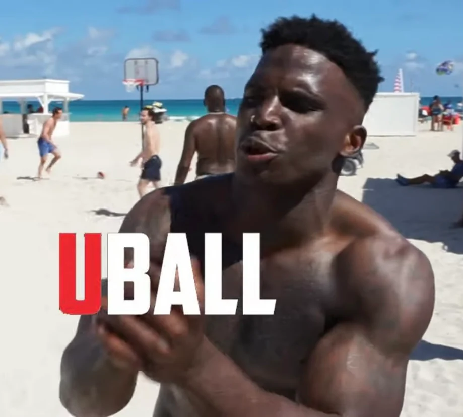 Man on beach with basketball hoop, text 'UBALL' overlay.