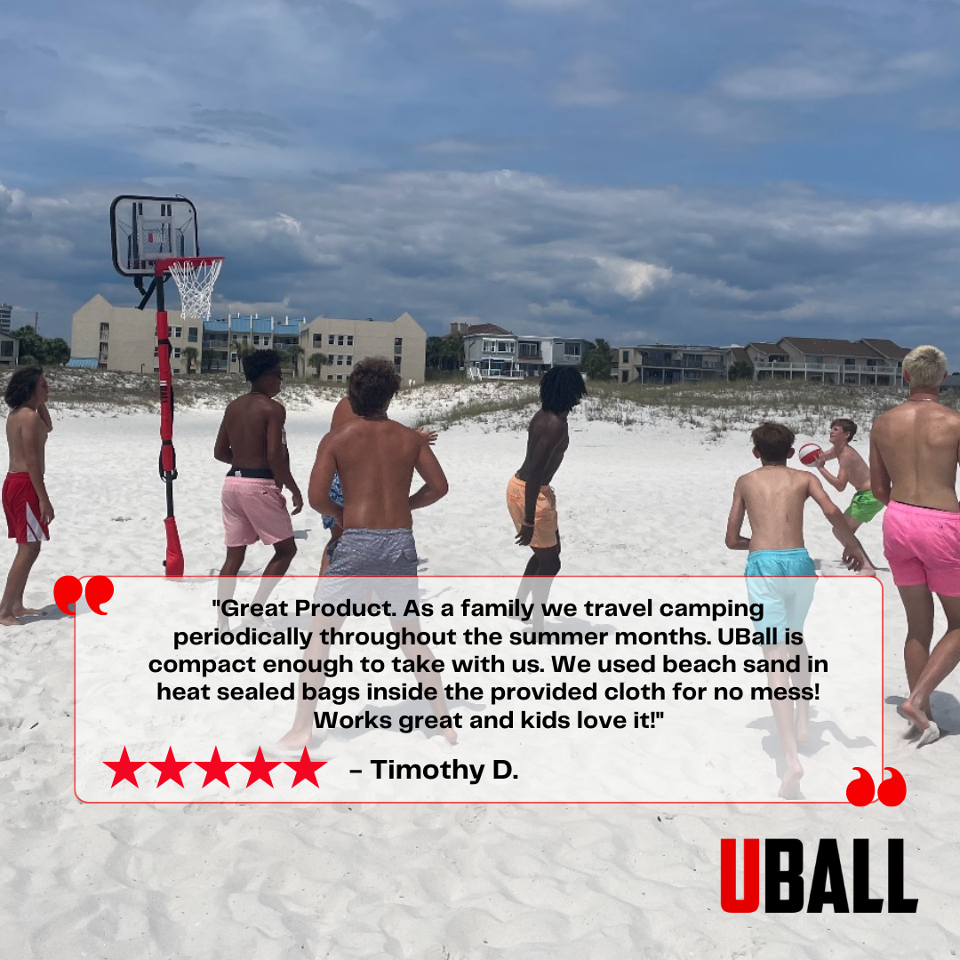 Group of people playing basketball on a beach with a portable hoop.