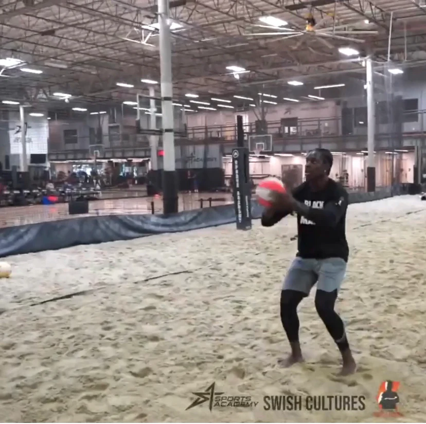 Person playing with a ball on an indoor sand court.
