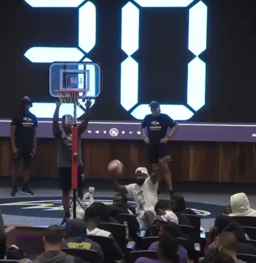 Indoor basketball game with a digital scoreboard and audience watching.