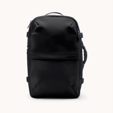 A black travel backpack with top and side handles, viewed from the front against a white background.