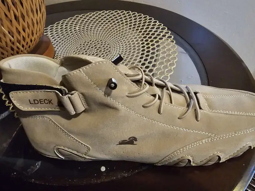 Beige high-top sneaker with 'LDECK' label on a decorative table.