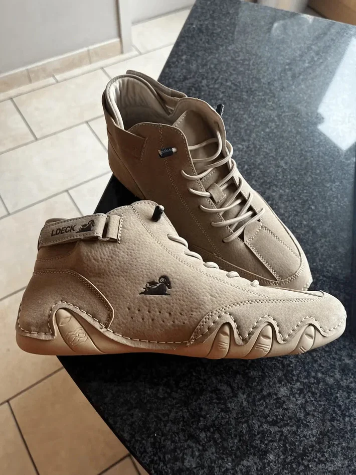Two beige sneakers with unique sole design on a dark surface.