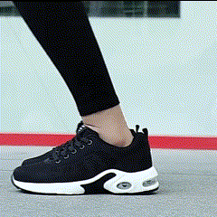 Person wearing black sneakers with white soles walking on a gray surface.