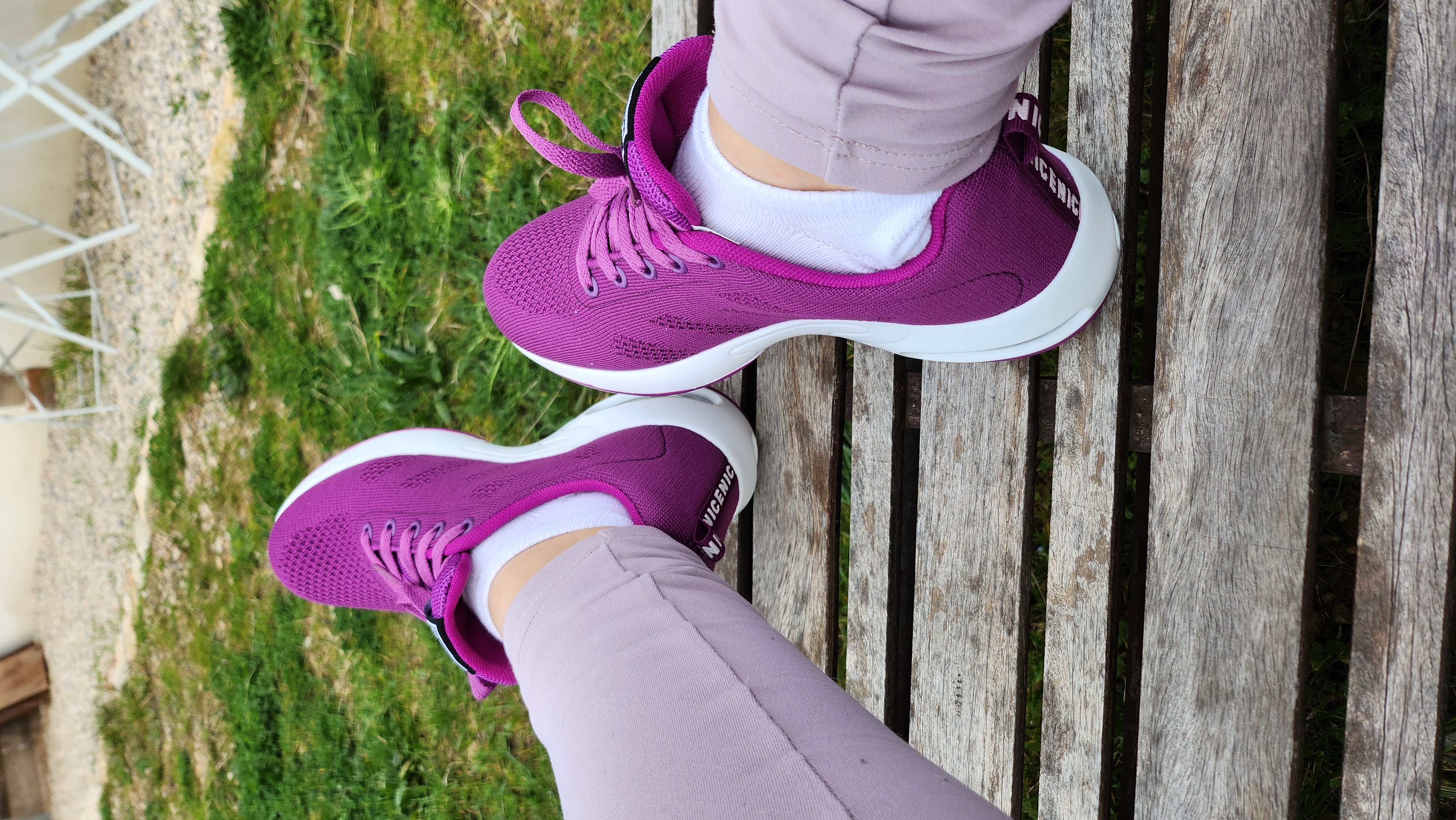 Person wearing purple sneakers and light pants on a wooden bench.