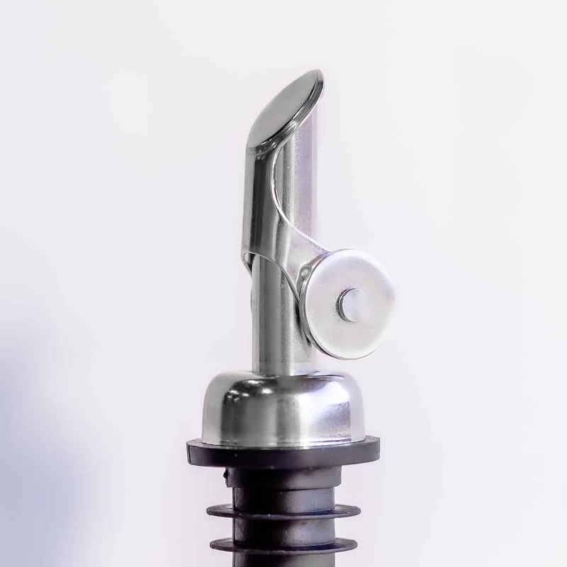 A close-up of a stainless steel bottle pourer with a hinged cap and rubber stopper.