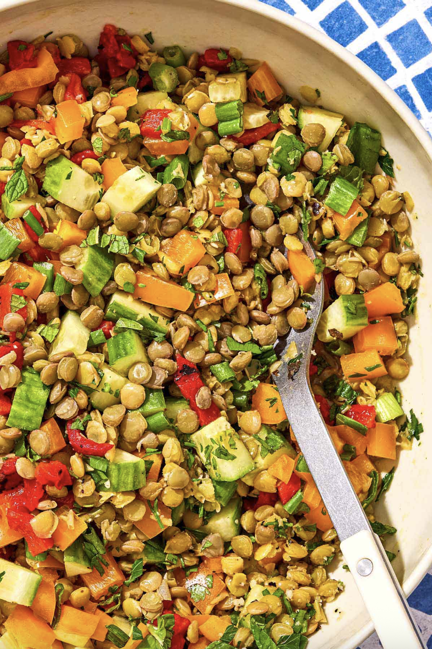 Colorful lentil salad with vegetables and herbs in a bowl.
