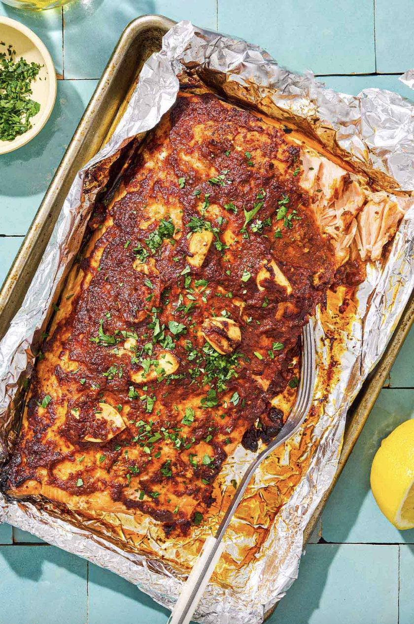 Baked salmon with herbs and spices on foil in a baking tray.