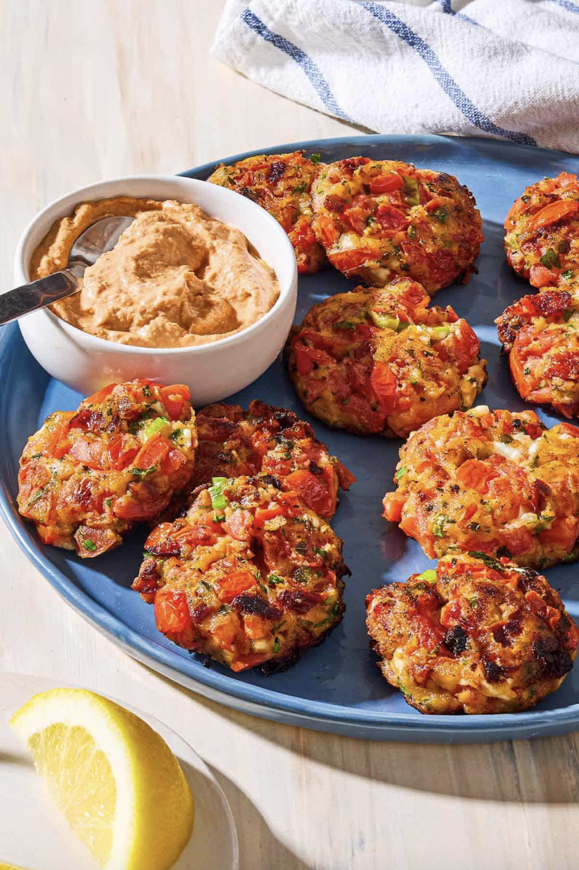 Plate of vegetable patties with a bowl of dip and a lemon slice.