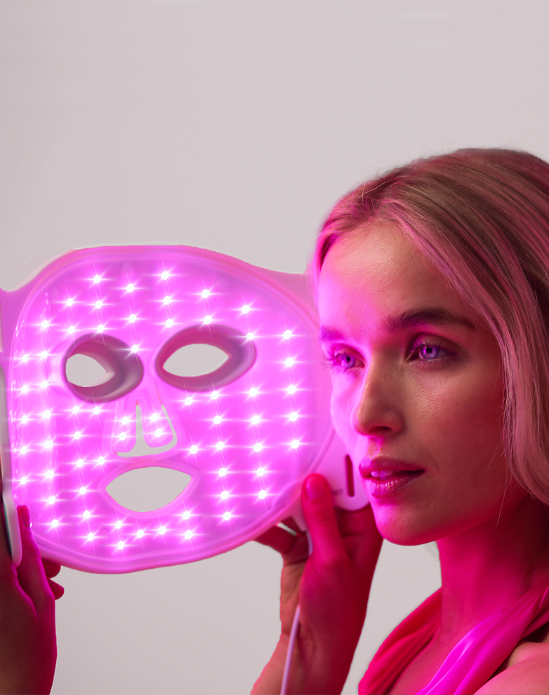 Person holding a glowing pink LED face mask.