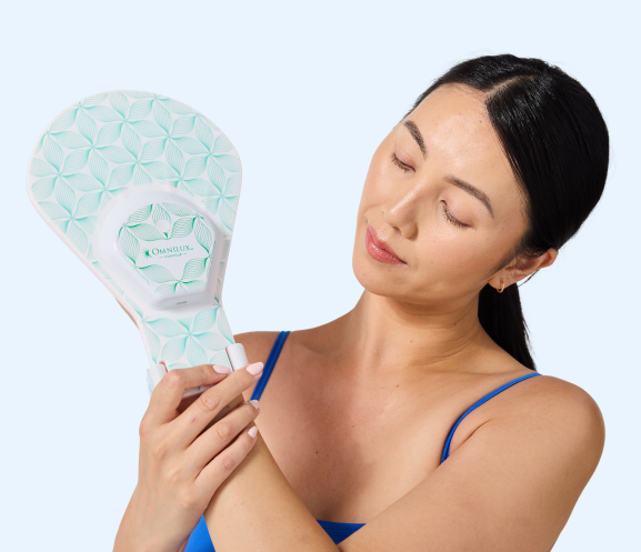 Person holding a patterned device with eyes closed, wearing a blue top.