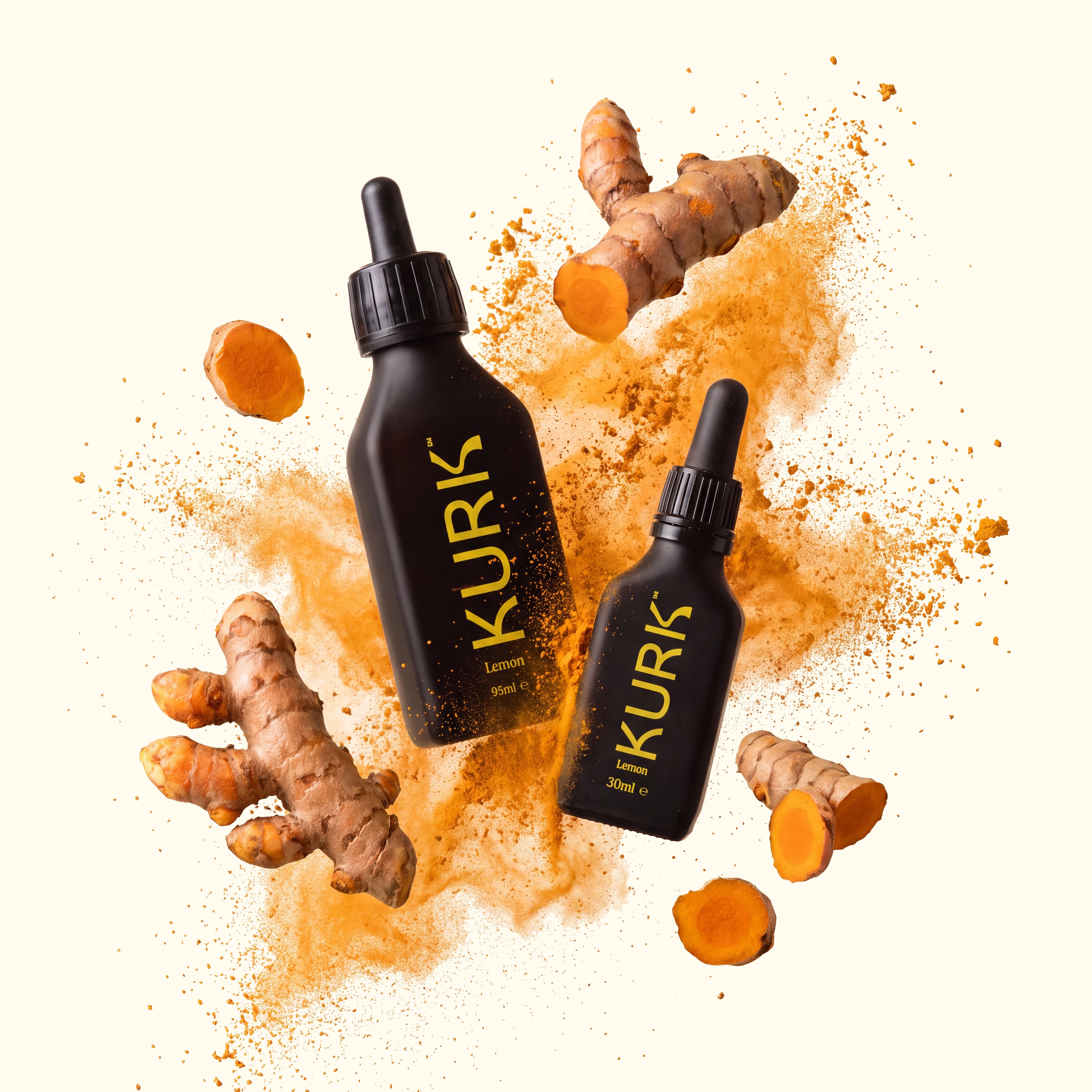 Two black KURK dropper bottles floating amongst fresh turmeric root and an explosion of turmeric powder.