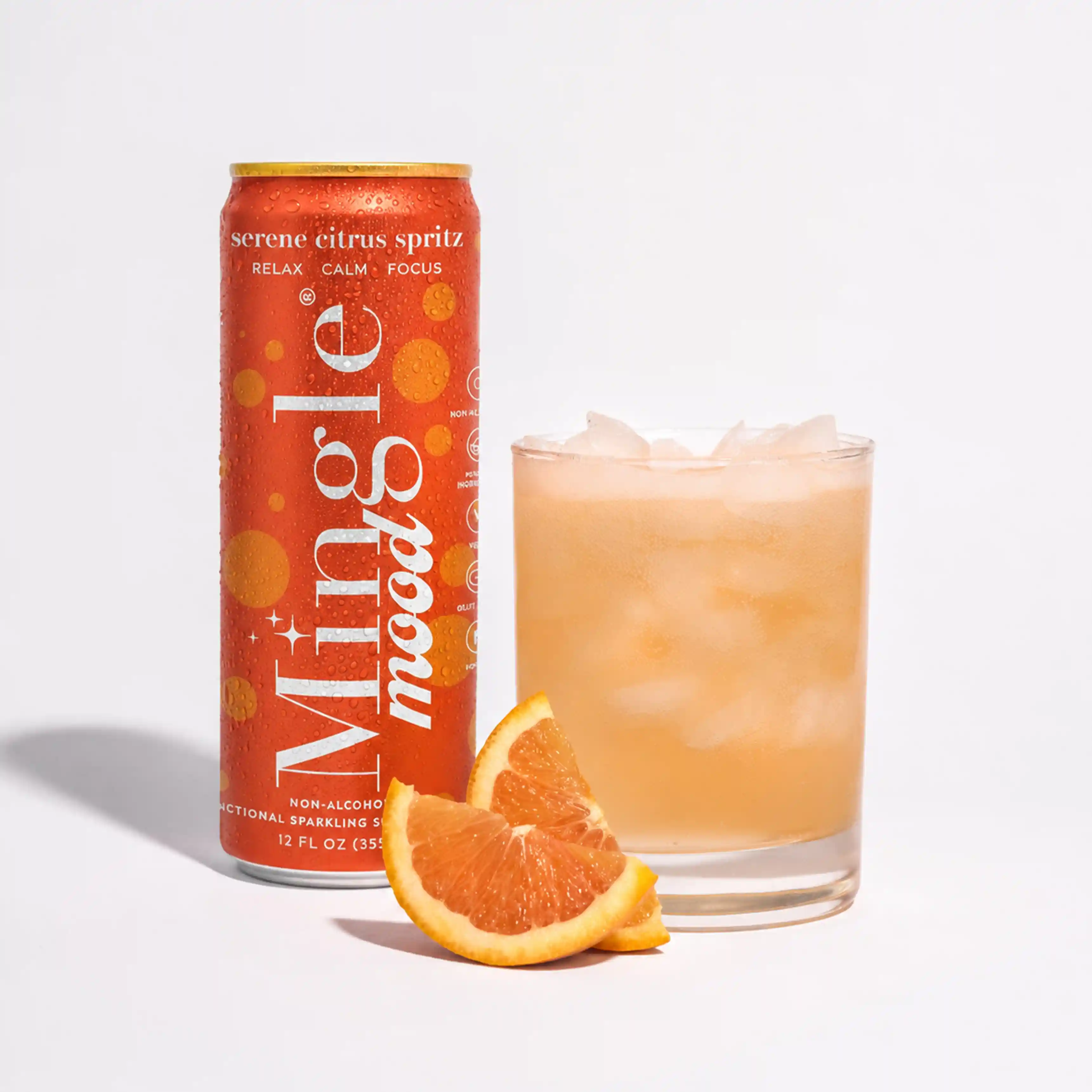 A can of Mingle Mood citrus spritz next to a glass of the drink with orange slices.