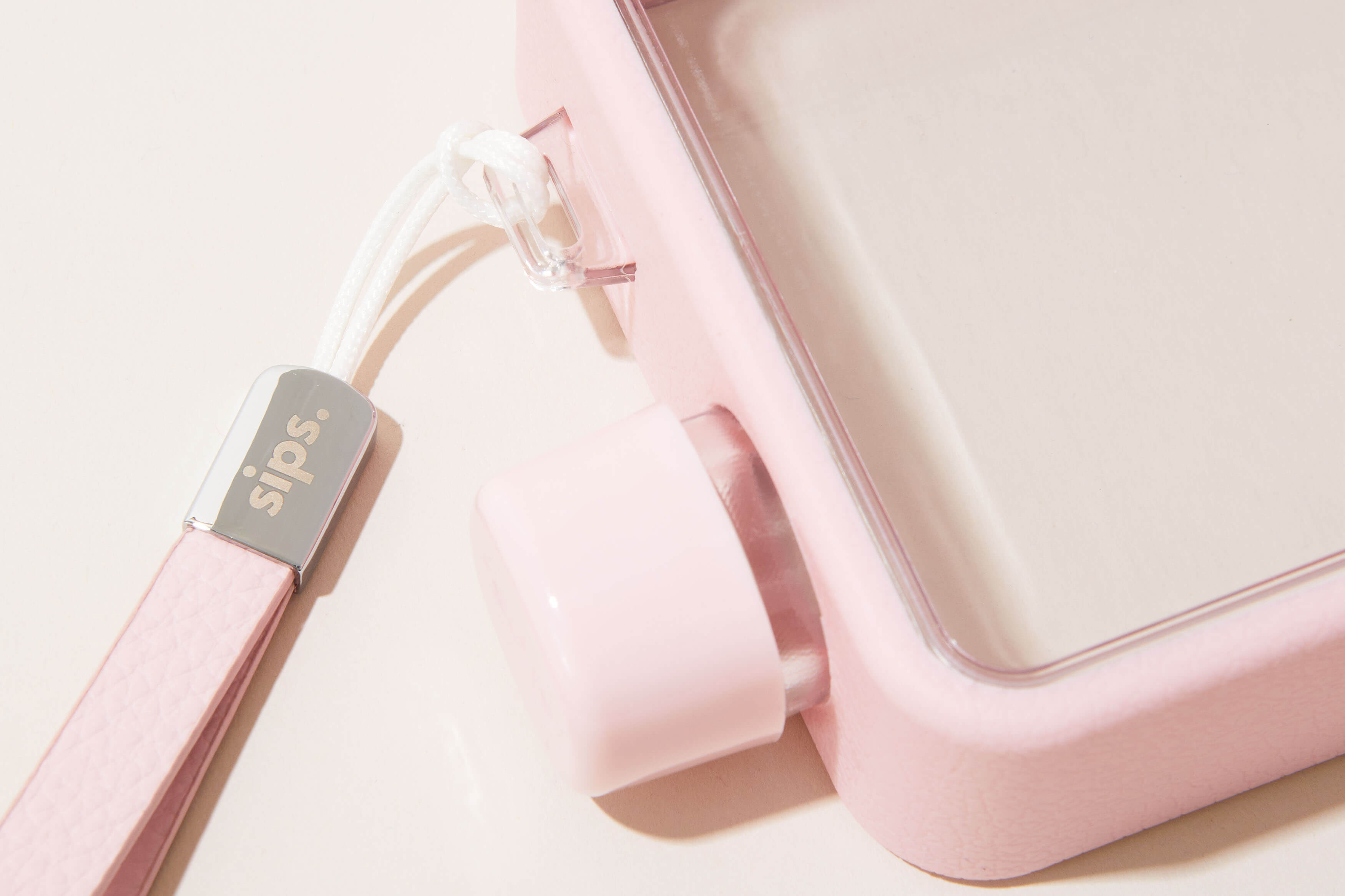 Close-up of a pink water bottle with a strap labeled 'sips.'