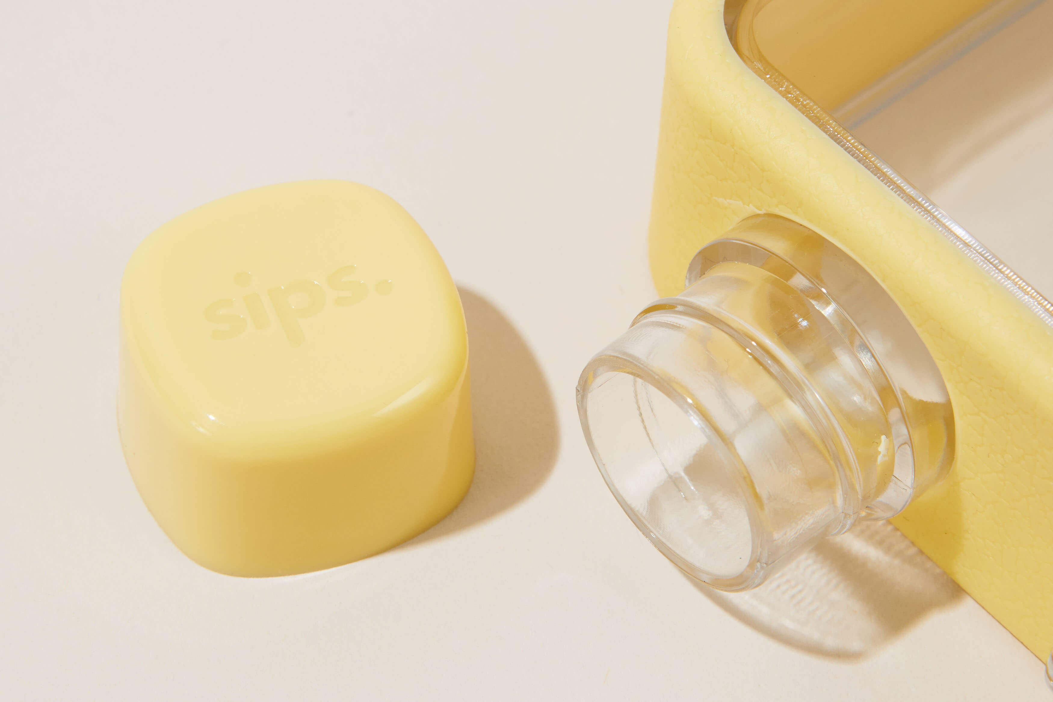 Yellow bottle cap with 'sips' text next to a clear bottle opening.