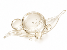 Clear, golden orbs of liquid with bubbles resting on a leaf-shaped splash against a white background.