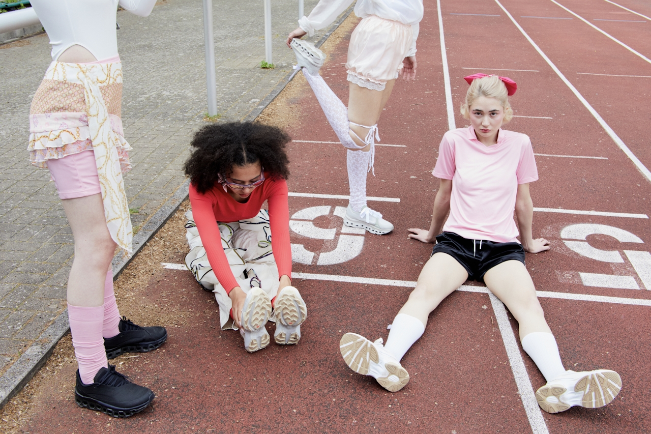 Four people in colorful outfits sitting on a running track.