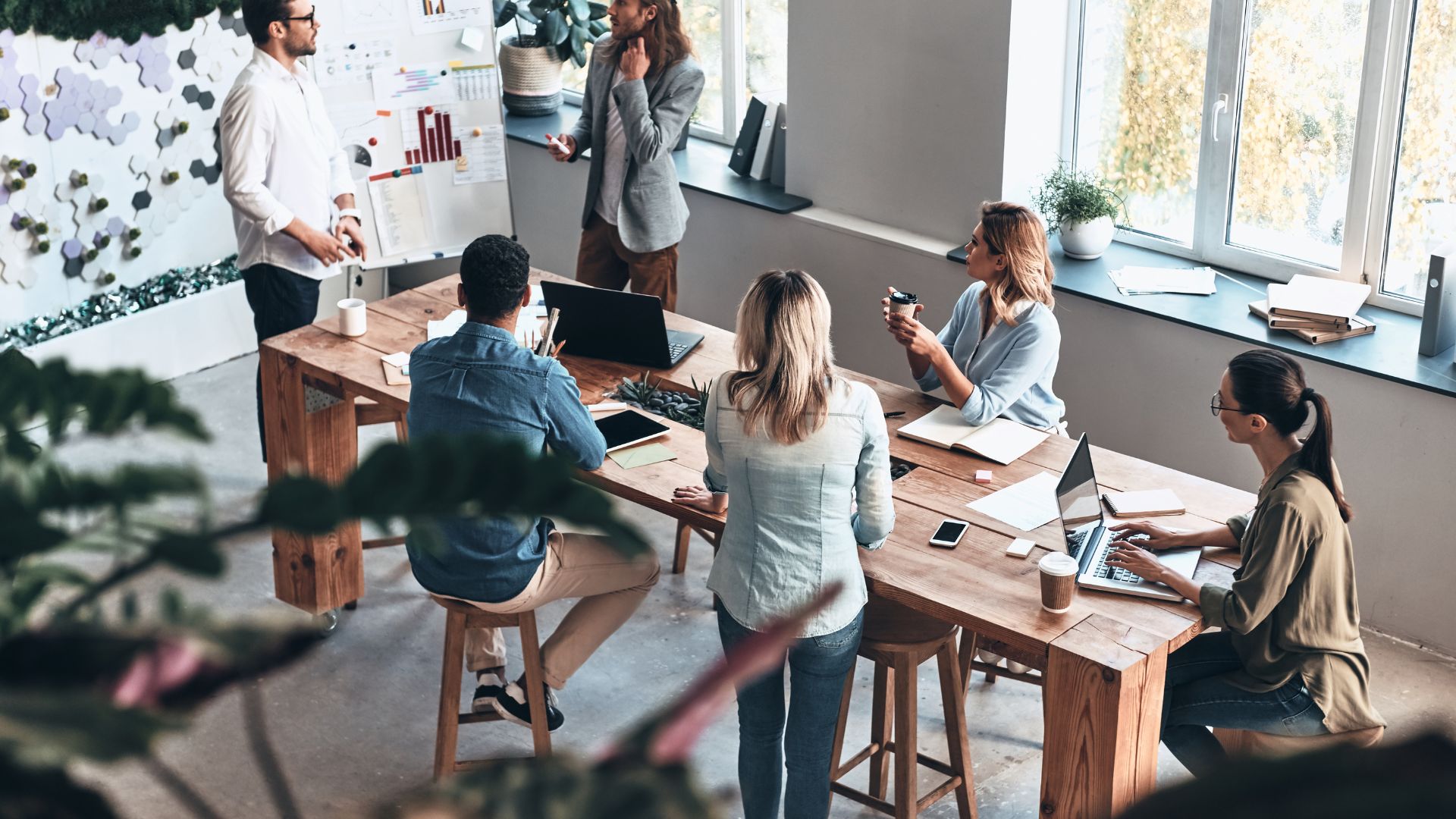 A high-angle view of a team of six coworkers collaborating in a modern office meeting space.