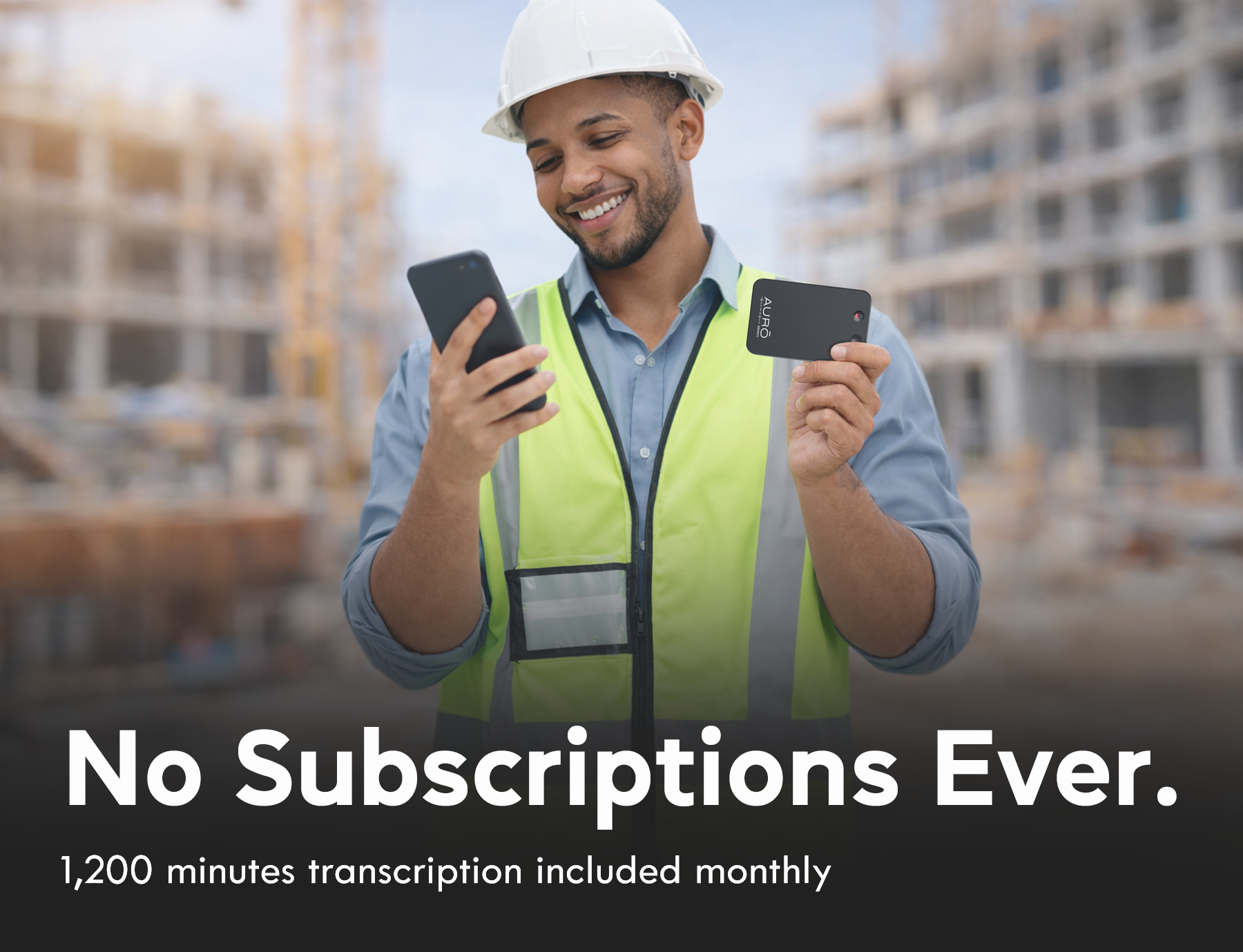A smiling construction worker in a hard hat holds a smartphone and a small device at a construction site.