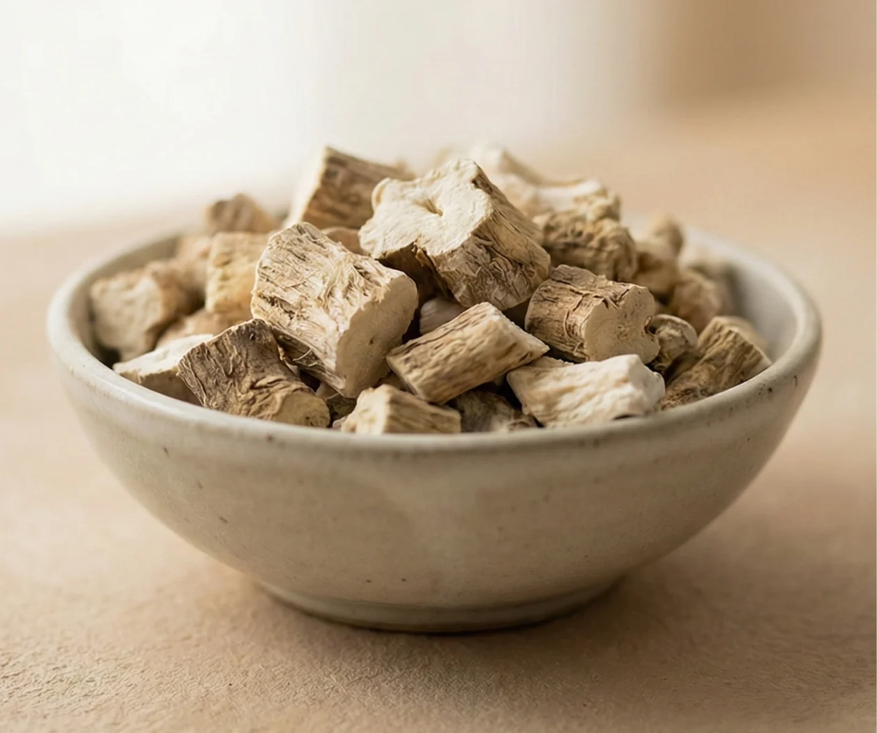 A close-up of a small, rustic bowl filled with dried, chopped root pieces.