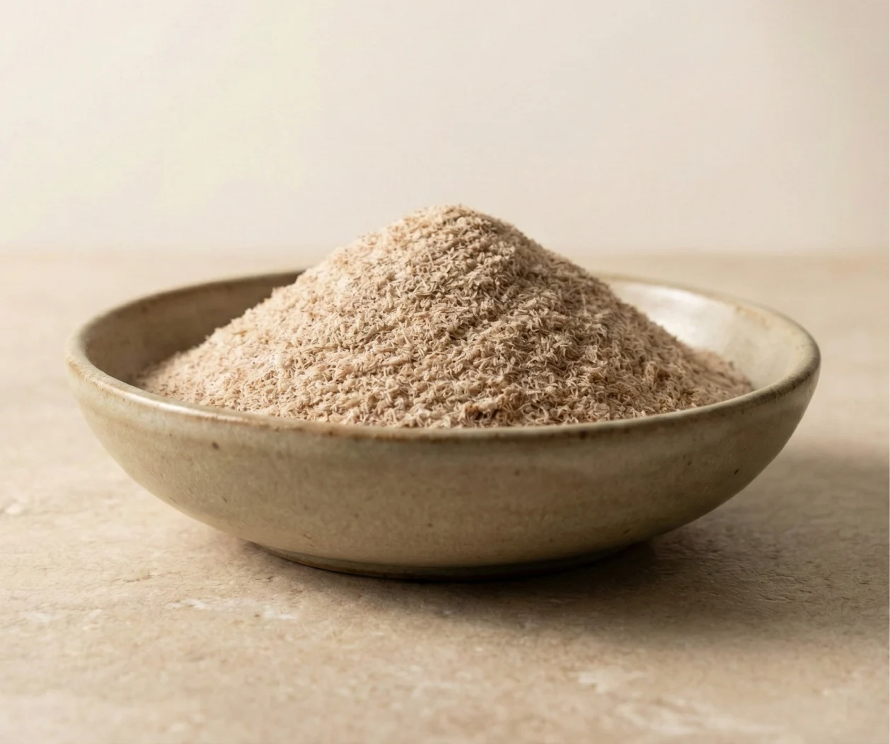 A shallow ceramic bowl filled with a heaping mound of a light brown, fibrous powder.