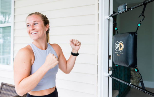 Woman smiling and exercising with a door-mounted punching pad.