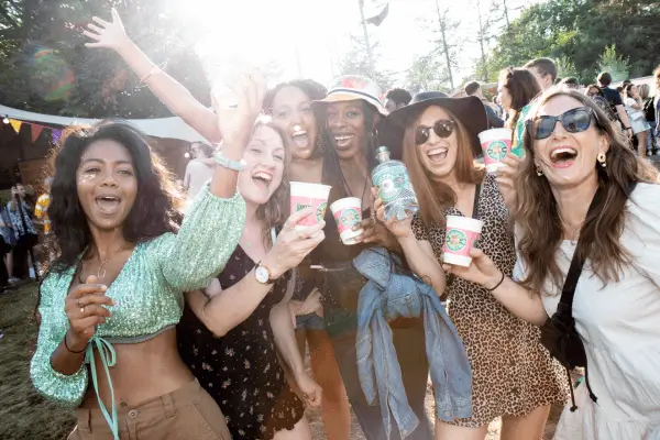 Group of women smiling and holding drinks at an outdoor event.